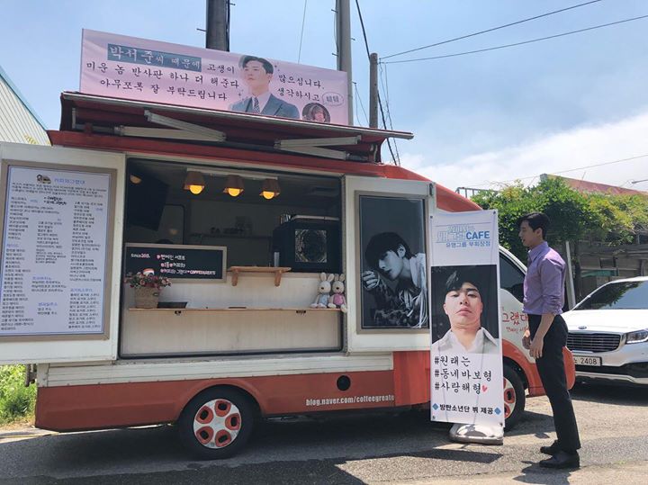 BTS V gửi xe tải đồ ăn tới phim trường “Why Secretary Kim?”. Banner ngang: “Vì anh Park Seo Joon mà mọi người phải vất vả rồi. Mong mọi người hãy cứ nghĩ là tốn thêm tấm hắt sáng cho một tên đáng ghét nữa và chăm sóc tốt cho anh ấy nhé ạ.” Banner dọc dưới