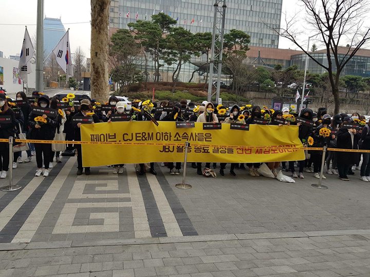 Fan JBJ cầm hoa hướng dương biểu t&igrave;nh trong im lặng trước cửa trụ sở Loen - nơi đặt chi nh&aacute;nh của Fave Entertainment chịu tr&aacute;ch nhiệm quản l&yacute; JBJ. Họ y&ecirc;u cầu xem x&eacute;t lại việc nh&oacute;m bất ngờ disband, đồng thời gửi đơn thư khiếu nại y&ecirc;u cầu giải th&iacute;ch về việc